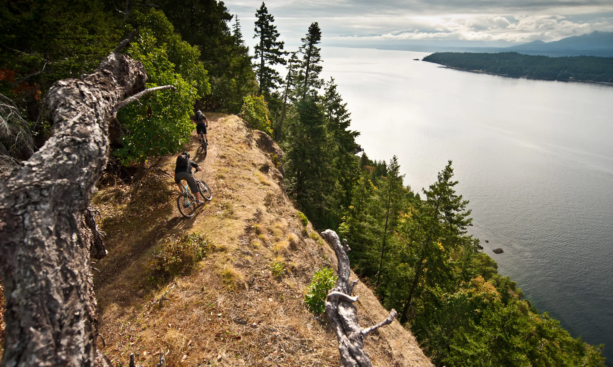 Mountain bikers riding a coastal ridge above the Salish Sea on Vancouver Island